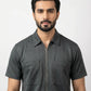 Man wearing a dark gray short-sleeve shirt with a collar on a white background