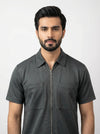 Man wearing a dark gray short-sleeve shirt with a collar on a white background