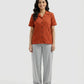 Woman wearing a rust-colored button-up shirt and gray pants on a white background