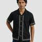 Man wearing a black embroidered shirt on a white background