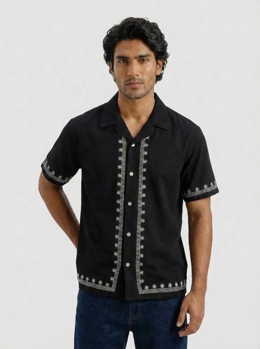 Man wearing a black embroidered shirt on a white background