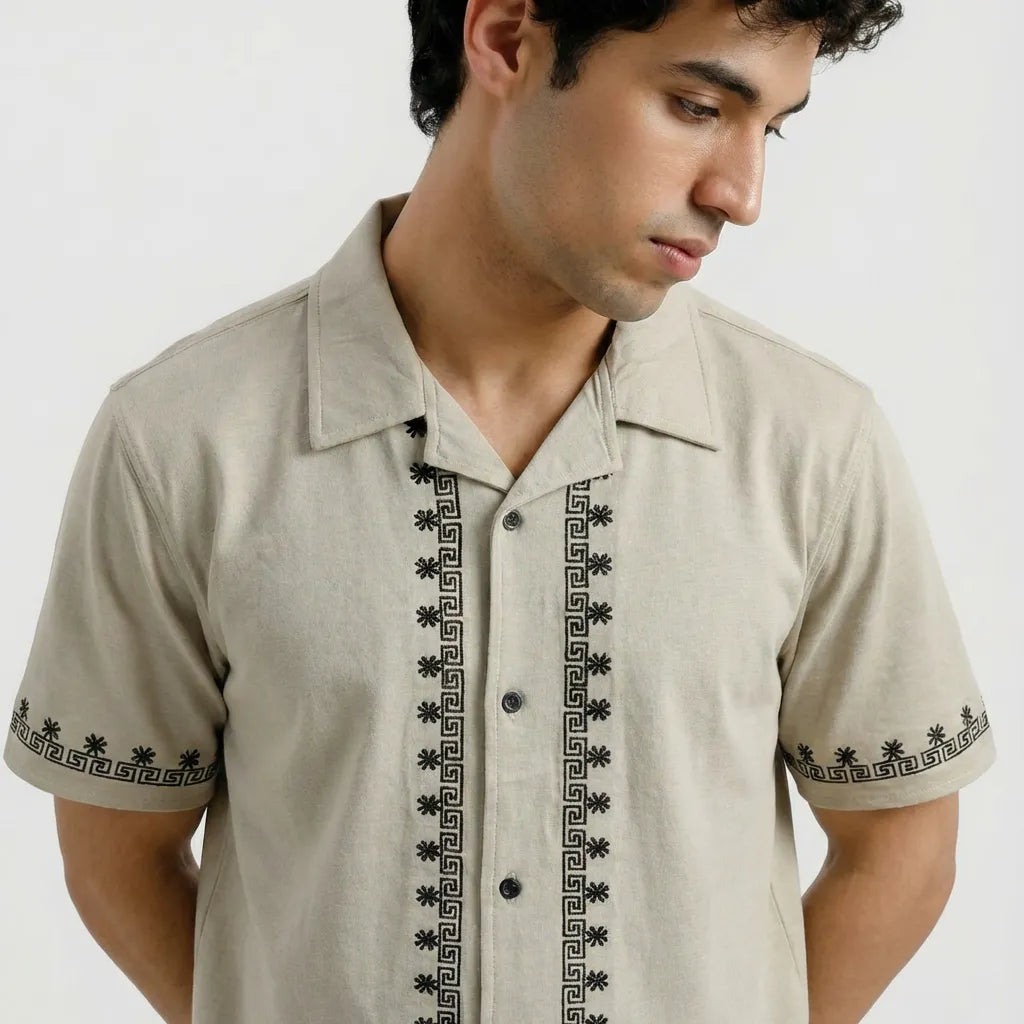 Man wearing a beige shirt with black embroidery on a white background