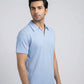 Man wearing a light blue polo shirt against a gray background