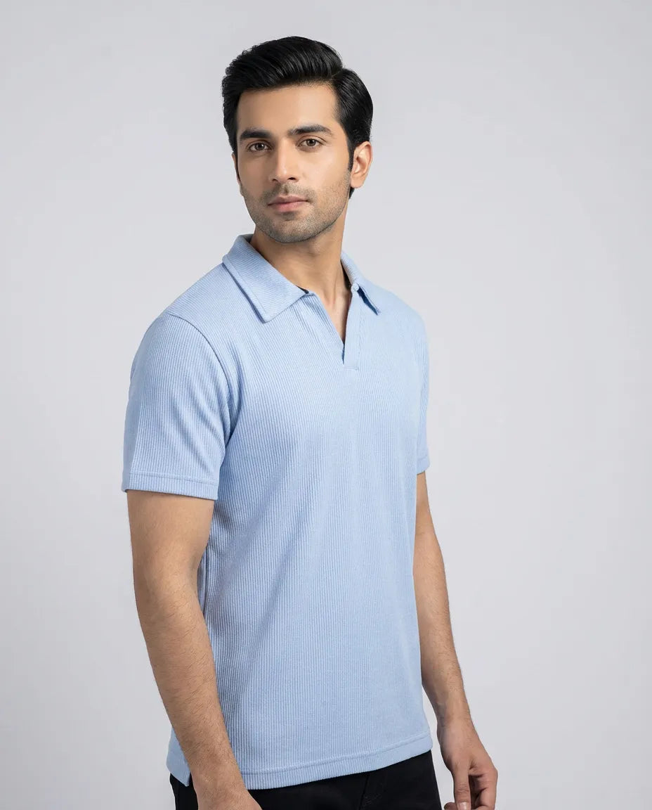 Man wearing a light blue polo shirt against a gray background