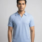 Man wearing a light blue polo shirt against a gray background