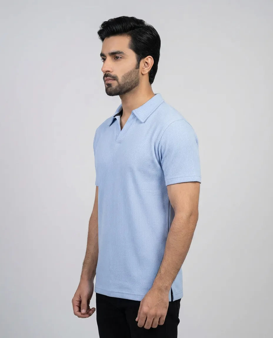 Man wearing a light blue polo shirt against a gray background