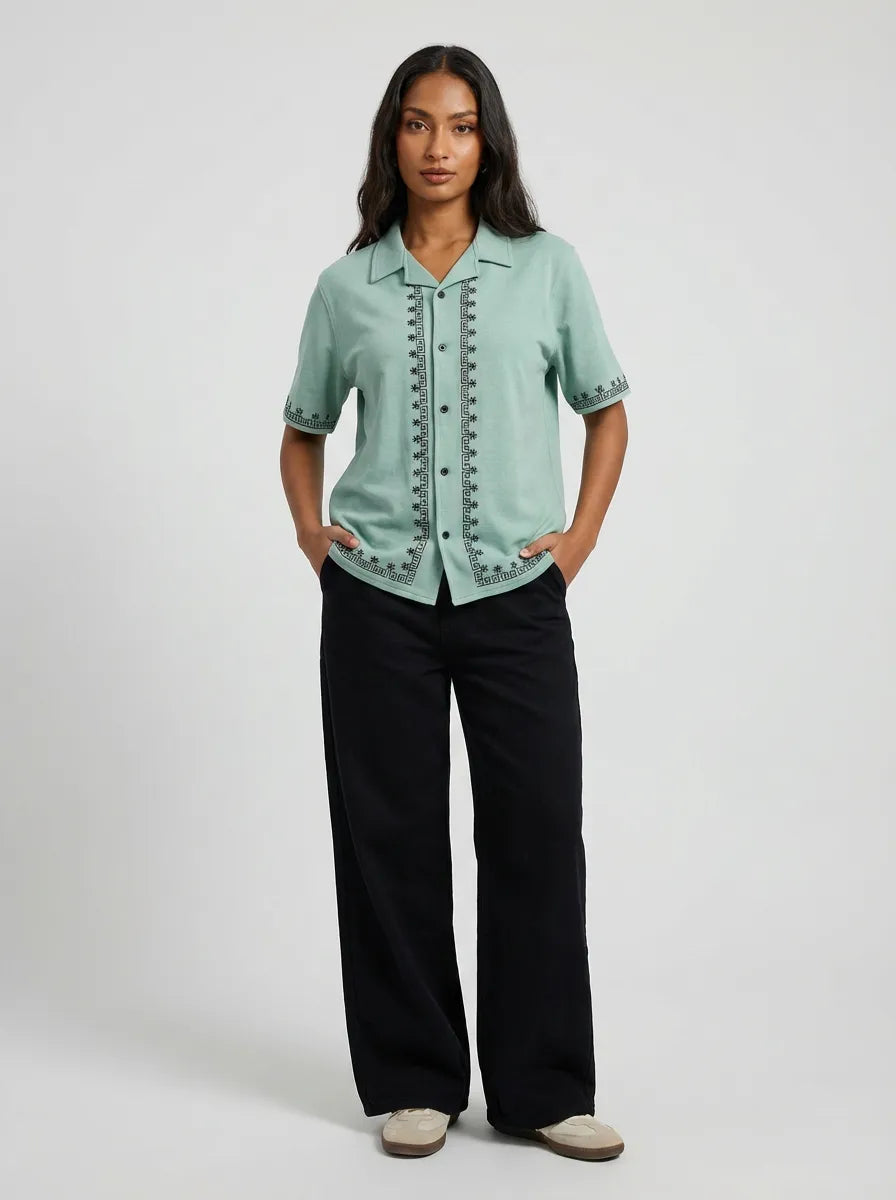 Woman wearing a light green blouse with black pants on a white background