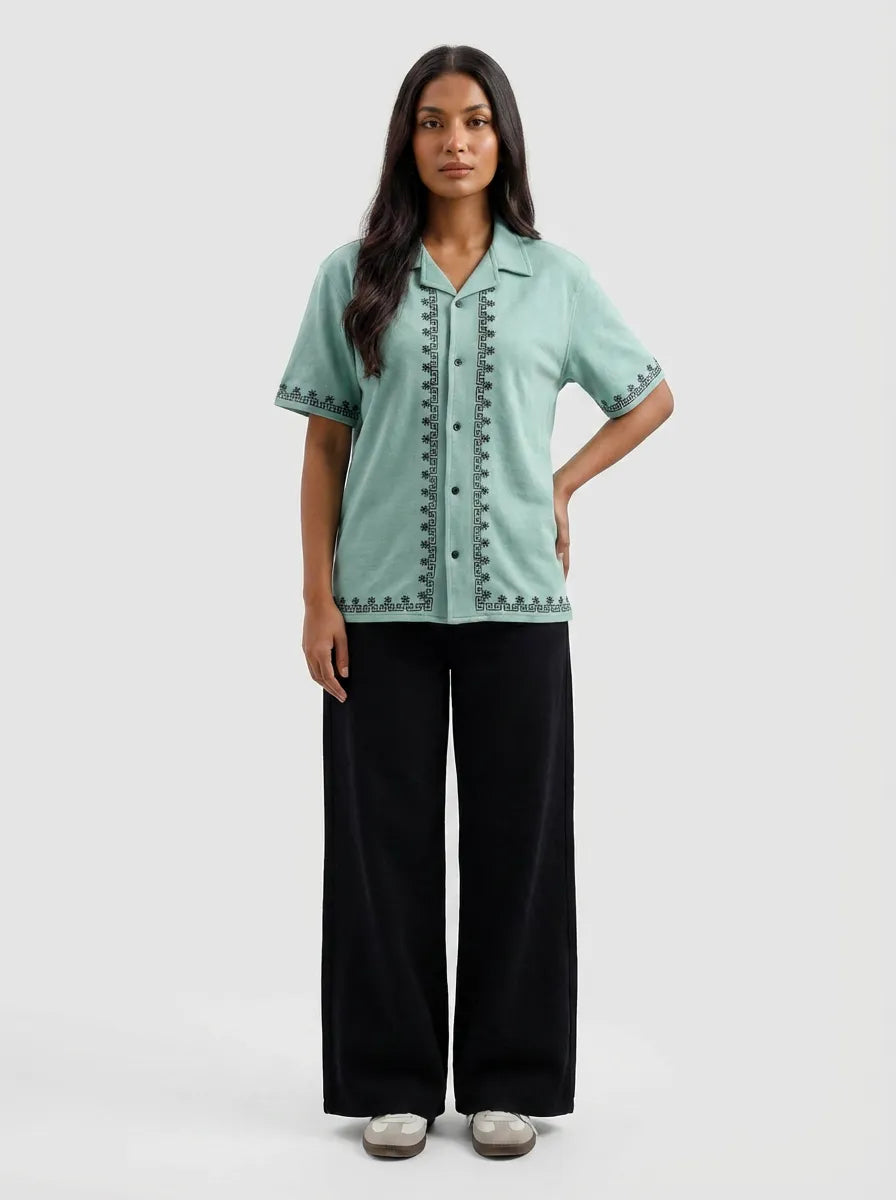 Woman wearing a light green shirt with black pants on a white background